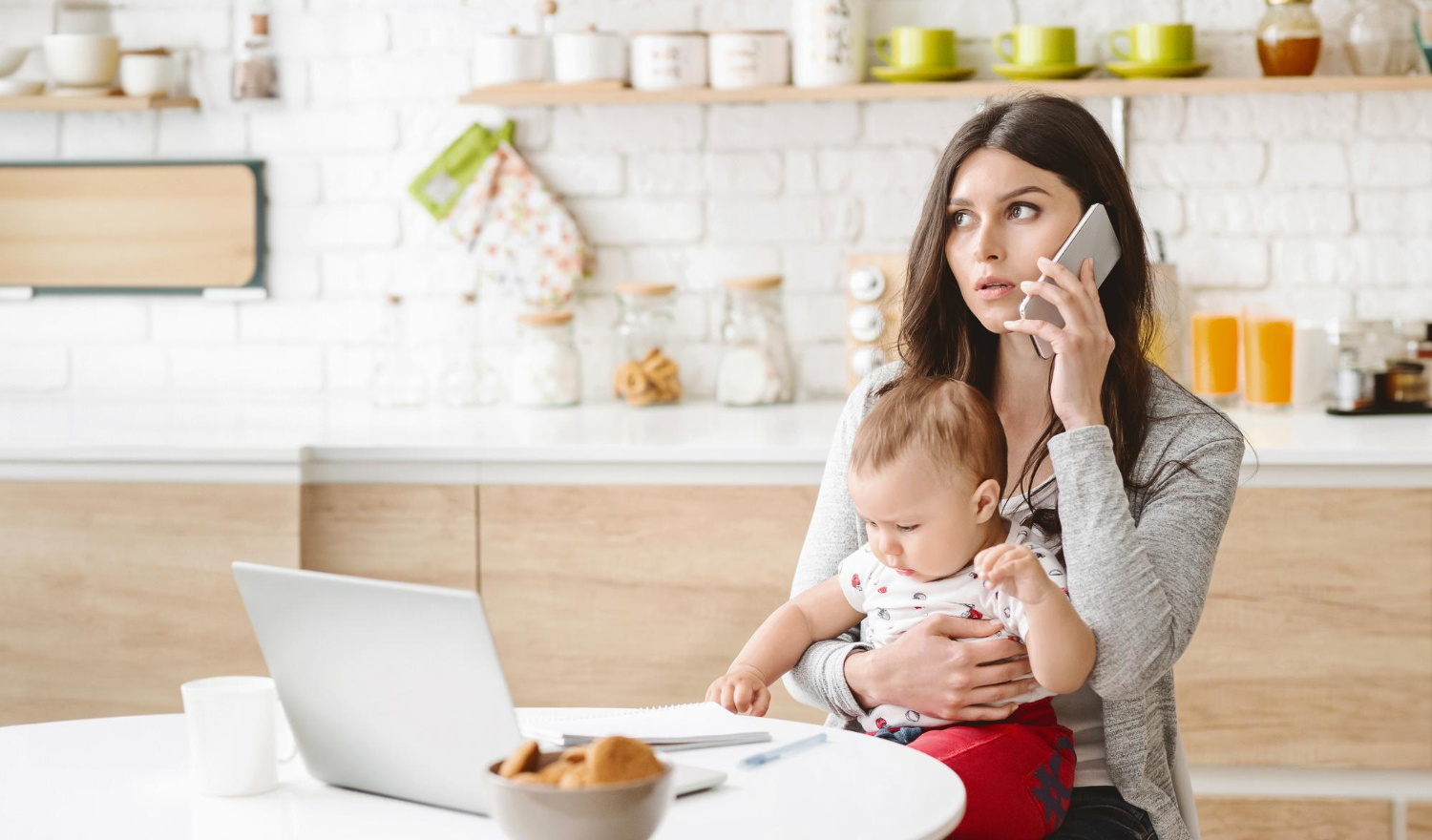 Mother holding her baby while on the phone